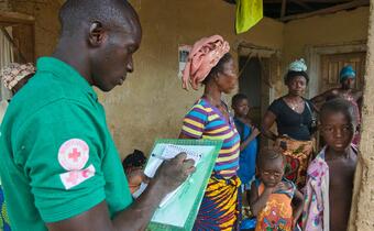 A man talks to a family about recent occurrences in their village in the Kambia district of Sierra Leone as part of the Red Cross Community Events Based Surveillance (CEBS) program