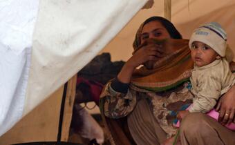 A mother and her son seek shelter from the rain in her family's tent at a Red Crescent camp in Charsadda, Pakistan in 2010