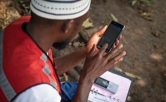 A Uganda Red Cross volunteer uses his smartphone to access resources about community epidemic and pandemic preparedness to help his work in his local community