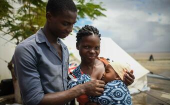A mother and father stand with their baby in Beira, Mozambique following Cyclone Idai in 2019