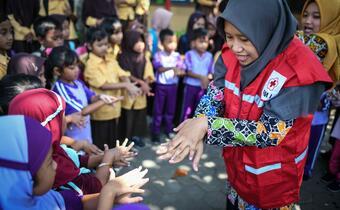 A volunteer from the Indonesian Red Cross teaches children about correct handwashing as part of a community epidemic and pandemic preparedness project funded by USAID
