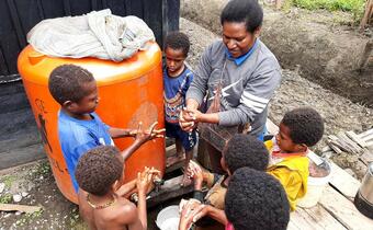 Indonesian Red Cross volunteers carry out community engagement work with children on safe handwashing in Papua New Guinea as part of their response to COVID-19