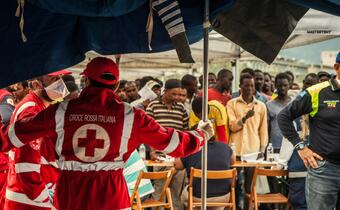 Italian Red Cross volunteers and staff welcome 578 migrants off an Italian Coastguard boat to the port at Messina, Sicily, in July 2015