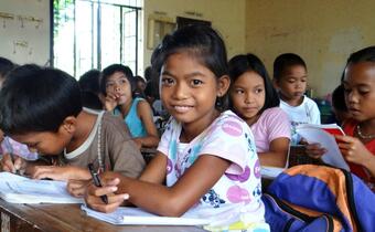 Children in a school in Leyte, Philippines smile and learn during class. Following Typhoon Haiyan, the American Red Cross repaired badly damaged classrooms, constructed new latrines and installed hand water pumps to help them resume their education