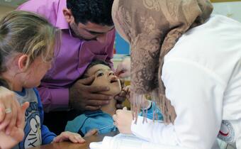 An oral polio vaccine is administered to a child at a Syrian Arab Red Crescent dispensary in Homs