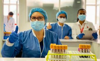 Medical staff with the Colombian Red Cross smile for the camera as they work in a lab as part of the response to the COVID-19 pandemic