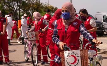 Tunisian Red Crescent volunteers respond to the COVID-19 pandemic in May 2020, using bicycles to distribute relief items and cash assistance