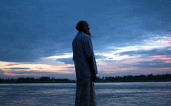 A man in Tangail, Bangladesh looks out at the land near his house which was severely flooded in August 2020, damaging his livestock and home and forcing him and his family to live in a boat