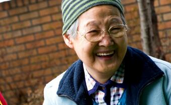 An older woman in Gyongi province, Seoul smiles as she laughs and jokes with a Korean Red Cross volunteer helping her with her laundry