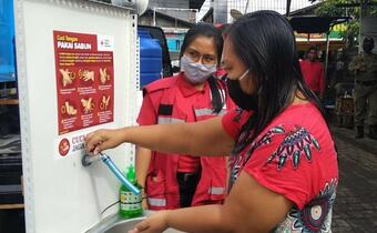 A volunteer from the Indonesian Red Cross runs community engagement activities in Bali in July 2020 to help people understand how to properly wash their hands and reduce their risk during the COVID-19 pandemic