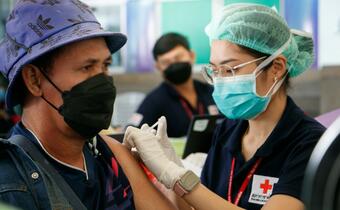 A Thai Red Cross volunteer nurse administers a COVID-19 vaccine in December 2021 to a man who had migrated to the country, as part of a vaccination service programme for migrant populations who have not been vaccinated before.