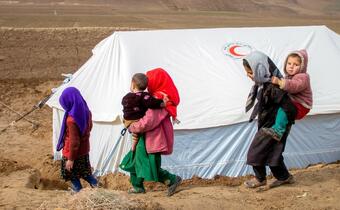 Children in north-western Afghanistan walk past a temporary shelter set up by the Afghanistan Red Crescent to house families in the aftermath of earthquakes in January 2022.