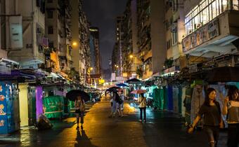 A shot of a rainy street in Hong Kong in 2018 with people walking with umbrellas. Hong Kong has been experiencing rising temperatures and more intense rainfall in recent years due to climate change.