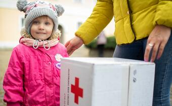 Little Hanna from Kharkiv stands with her mother to collect a hygiene kit from the Ukrainian Red Cross as they make their way out of Ukraine in late March 2022.