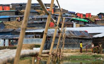 A boy stands on a wooden bridge surrounded by temporary shelters in Cox's Bazar, Bangladesh in 2017.