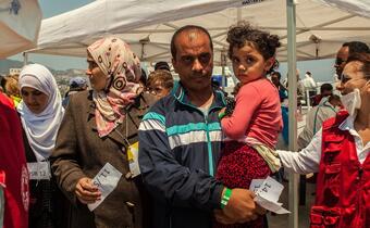 Italian Red Cross volunteers and staff welcome migrants off an Italian Coastguard boat at the port of Messina, Sicily in 2015, where they also provide food and water, health checks and psychosocial support.