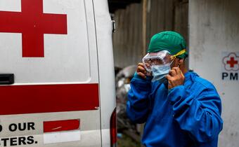 A medical worker puts on personal protective equipment outside a COVID-19 hospital in Bogor, Indonesia, run by the Indonesian Red Cross so he can safely treat, test and vaccinate people against the virus.