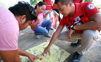 A Philippine Red Cross volunteer uses a hand drawn map to explain disaster risks to a community and identify the safest place to be in the event of flooding.