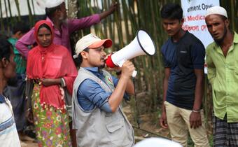A Bangladesh Red Crescent Society volunteer uses a megaphone to explain the restoring the family links programme at their booth set up in Hakimpara Camp in Bangladesh in 2017.