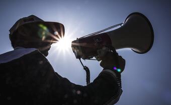 A Bangladesh Red Crescent Society volunteer uses a megaphone to communicate early warning and preparedness messages about an upcoming cyclone to his community.