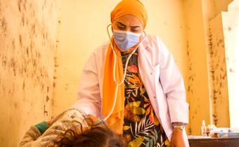 An Egypt Red Crescent Society health worker performs a health check on a girl in a mobile health clinic during the COVID-19 pandemic.
