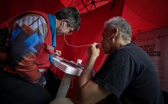 A member of an Argentine Red Cross HSP team helps a migrant get in touch with family.
