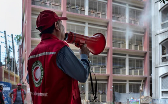 Red Crescent volunteer gives information through a bullhorn