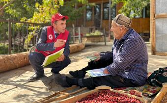 A Tajikistan Red Crescent volunteer in the remote region of Mullamir speaks to a cattle owner about the risk of zoonotic diseases and explains how he can recognize and report signs of disease in his cows.