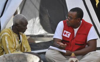 An IFRC staff member speaks with a man who was displaced from his home in Mali.