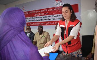 Clara Amato, IFRC Migration Coordinator for the emergency operation in Rosso, hands an envelope containing cash to a vulnerable woman during the official launch of the cash assistance program, which targets 600 vulnerable host families. 