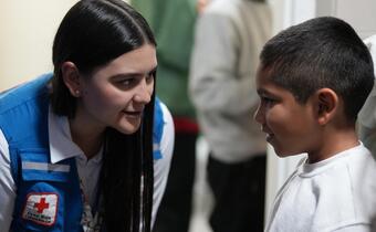 Elizabeth Becerra, leader of the Colombian Red Cross migration team, talks with a child who arrived on a return flight to El Dorado Airport. 