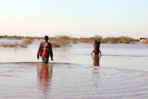 A Sudan Red Crescent Volunteer wades through deep water to reach a woman affected by severe flooding in Khartoum East in August 2020