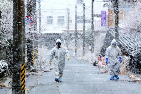 Des volontaires de la Croix-Rouge japonaise vêtus d'équipements de protection se promènent dans la ville de Namie pour aider à évacuer les résidents après l'accident de la centrale nucléaire de Fukushima Daiichi.