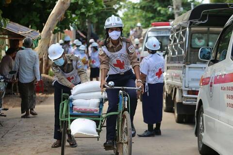 A volunteer wearing a COVID-19 facemask with the Myanmar Red Cross Society cycles to deliver humanitarian supplies to communities during a period of civil unrest in 2021