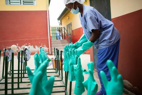 إمرأة تعمل في مرفق لعلاج وباء الإيبولا في نزريكور في غينيا، تقوم بتطهير الملابس الواقية الشخصية كجزء من الاستجابة لتفشي وباء الإيبولا في البلاد عام 2021