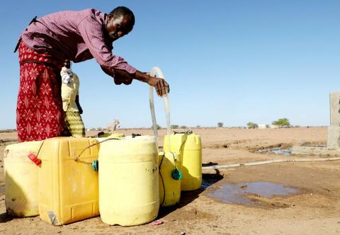 رجل في مقاطعة داداب في كينيا، يملأ أوعية المياه النظيفة من مضخة ركبها الإتحاد الدولي لجمعيات الصليب الأحمر والهلال الأحمر أثناء الجفاف السيئ في صيف 2021