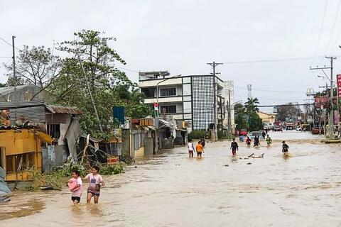 Peoplein Kabankalan City, Philippines wade through a flooded street after Typhoon Odette slammed into the coastal areas of Eastern Philippines on 16 December 2021 causing landslides and widespread flooding.
