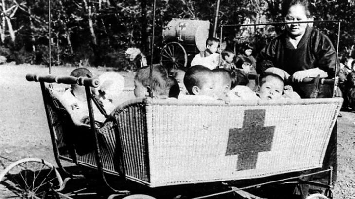 Una voluntaria de la Cruz Roja Japonesa cuidando de unos niños después del gran terremoto de Kantō en 1923