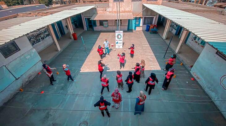 Young women gather in a courtyard in Iraq to learn about promoting a culture of non-violence and peace through sport