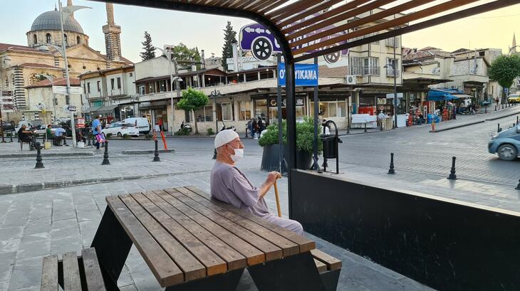 A shot of a man sat at a bus stop in Türkiye by ESSN Storyteller, Ahmed. Ahmed says "This photo is about an old man who was sitting at a bus stop.  And when I sat next to him and we talked, he started talking about his memories in his city,  Aleppo and how he feels that Turkey is his last stop in this life."