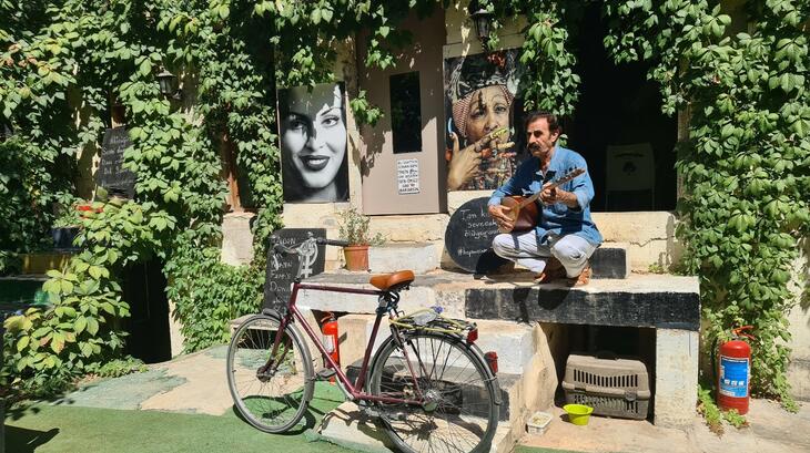 لقطة لفنان سوري يعمل في مقهى في غازي عنتاب. يجلس ويعزف الموسيقى بجانب دراجته. الصورة التقطها الحكواتي ضمن مشروع برنامج شبكة الأمان الاجتماعي في حالات الطوارئ علاء. 