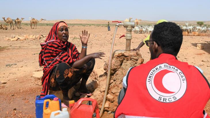 متطوع في جمعية الهلال الأحمر الصومالي يستمع إلى امرأة في نوغال في الصومال تتحدث عن تأثير الجفاف على حياتها وسبل عيشها. إنّ ازدياد الطلب على نقاط المياه المتبقية التي لم تجف، أجبرها على قضاء المزيد من الوقت في جمع المياه، بالتزامن مع رعاية أسرتها في المنزل. 
