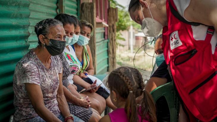 Una delegada de la IFRC habla con un grupo de mujeres en Honduras en mayo de 2022 durante una sesión de participación comunitaria para entender cómo se están recuperando de los huracanes Eta e Iota hace un año.