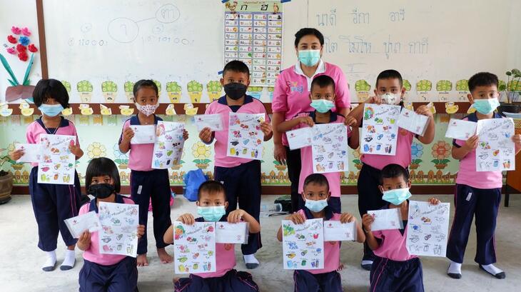 مجموعة من تلاميذ المدارس في مقاطعة ناخون سي ثمرات في تايلاند يرفعون ملصقات ملونة حول التأهب للكوارث كجزء من جلسة تدريبية نظّمتها جمعية الصليب الأحمر التايلاندي في أواخر مايو/أيار 2022.