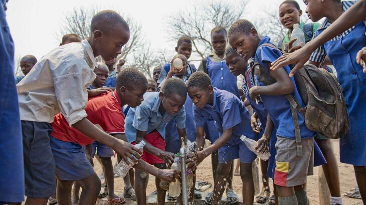 Niños de la escuela primaria Chiwenga de Muzarabani, en el norte de Zimbabue, obtienen agua potable de un grifo instalado por Cruz Roja. La zona es una de las más marginadas del país y está sometida a sequías e inundaciones recurrentes. 