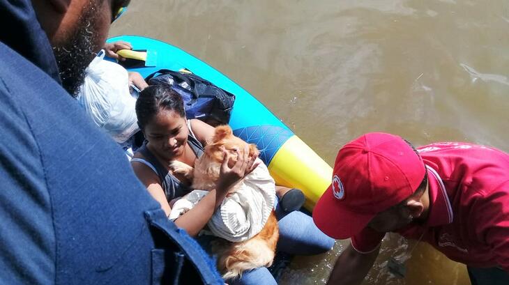 Trinidad & Tobago Red Cross volunteers rescue a woman and her dog who were stranded in flood water following flooding in the parts of the country in November 2022. The National Society is still supporting affected communities to recover, with support from the IFRC's Disaster Response Emergency Fund (DREF).
