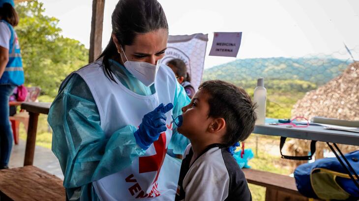 عاملة صحية في الصليب الأحمر الفنزويلي تقوم بفحص طفلاً صغيراً في قرية ريفية في ولاية بورتوغيزا. 