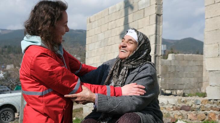 Turkish Red Crescent staff member, Tuba, speaks with Elif, who lost her husband and home in the earthquake, near the town of Nurdağı, Türkiye, in February 2023. After spending some time together talking, Elif manages a smile and reaches out for a hug.