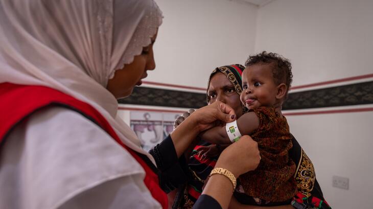 Un volontaire du Croissant-Rouge de Somalie mesure le tour de bras d'un petit enfant dans une clinique de Burao afin de vérifier qu'il ne souffre pas de malnutrition, alors que l'insécurité alimentaire et de nombreuses autres crises sévissent dans le pays.