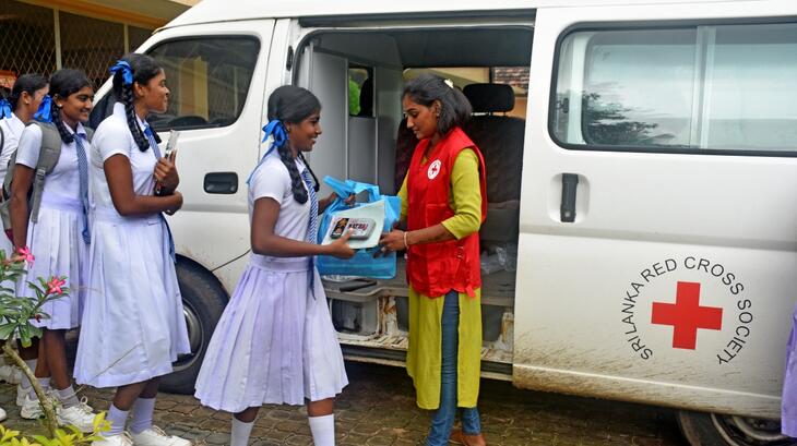 Une volontaire de la Croix-Rouge du Sri Lanka distribue des produits d'hygiène menstruelle à des écolières à Vavuniya, au Sri Lanka, en avril 2023. 